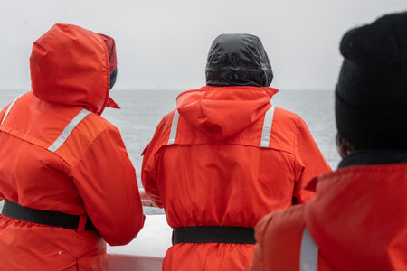 Rear view of whale watchers in orange full body life jackets sitting on a boat on Johnstone Strait, British Columbia, Vancouver Island, Canadaのeditorial素材
