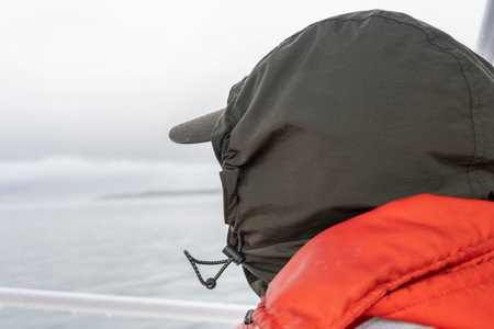 Rear view of a whale watcher in orange full body life jackets sitting on a boat on Johnstone Strait, British Columbia, Vancouver Island, Canadaのeditorial素材