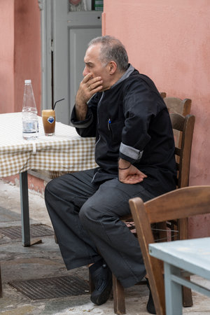 Elderly man seated at an outdoor cafe in Athens Greeceのeditorial素材