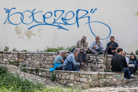 People sitting on a stone barrier in Athens Greeceのeditorial素材