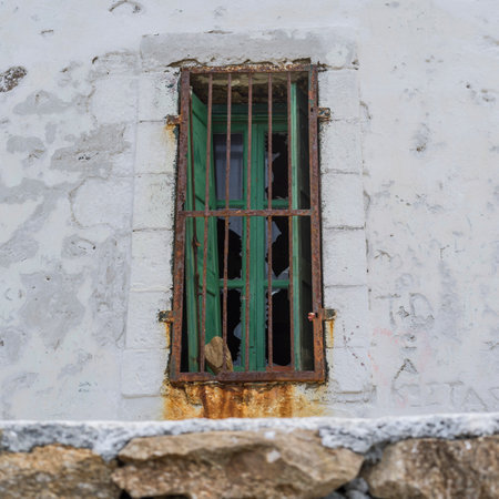 Bars on a broken weather worn window on Mykonos Island, Greeceのeditorial素材
