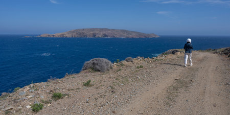 Female tourist wearing a helmet walking on a rocky trail on Mykonos Island Greeceのeditorial素材