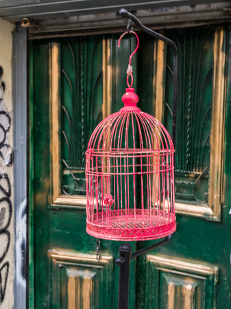 Pink bird cage suspended outside a door in Athens, Greeceのeditorial素材