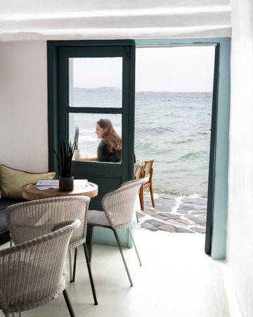 Woman seated on a waterfront patio, Little Venice, Mykonos Town, Mykonos Island, Greeceのeditorial素材