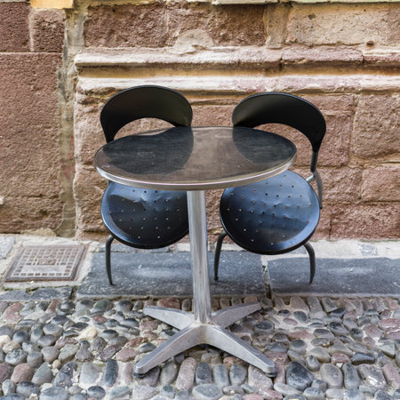 Two chairs behind a round table on a walkway in the Town of Bosa, Sardinia, itallyのeditorial素材