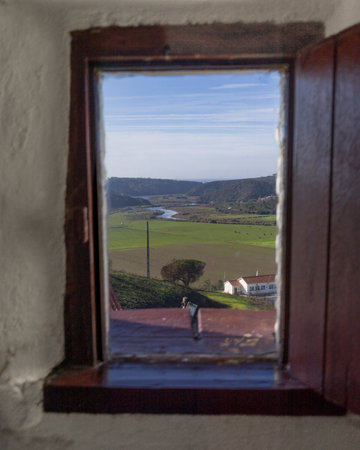 View through an open window of the landscape surrounding a village in Portuga that lies on the south bank of the Ribeira de Seixe, which here forms the border between the Algarve and Alentejo, Odeceixe, Faro, Portugalのeditorial素材