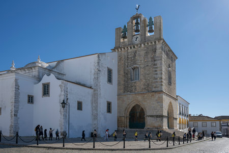 Tourists outside a cathedral in Faro which is the capital of southern Portugalâs Algarve region. The cityâs neoclassical Arco da Vila is on the site of a gate that was part of the original Moorish wallのeditorial素材