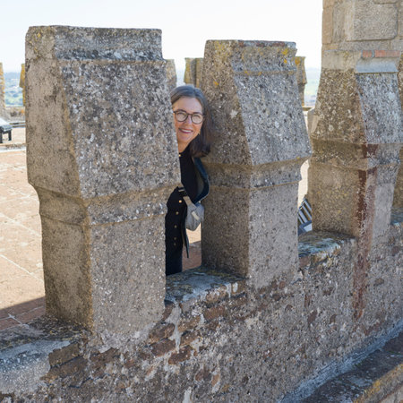 Female tourist looking through a section of a stone wall in Ãvora which is the capital of Portugal's south-central Alentejo region.  In the city's historic center stands the ancient Roman Temple of Ãvoraのeditorial素材