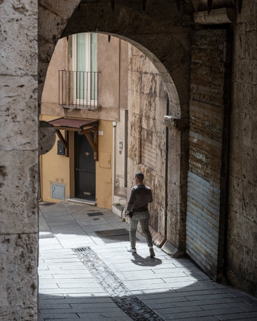 Man standing under a covered arched passageway, City of Cagliari, Sardinia, Italyのeditorial素材