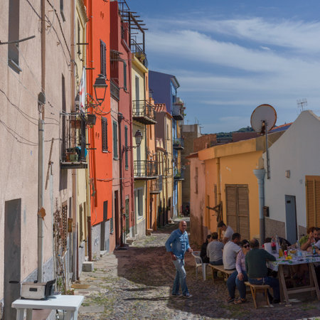 Group of people sitting at a table on a street in the Town of Bosa, Sardinia, Italyのeditorial素材