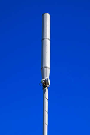 A mobile phone mast in a town in the UK seen against a clear blue skyの写真素材
