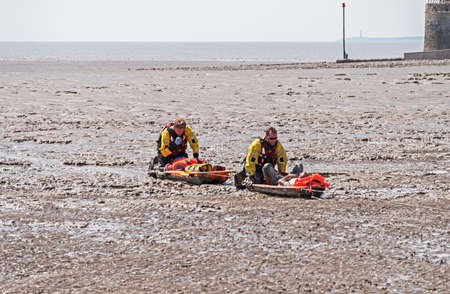 Weston-super-Mare, UK - July 16, 2018: Coastguards rescue a casualty from soft mud on the beach