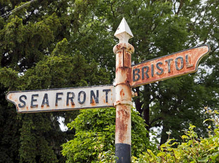 Weston-super-Mare, UK - June 17, 2019: An old, rusted signpost giving directions to the sea front and Bristol.のeditorial素材