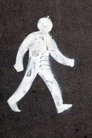 A sign consisting of a figure of a walking man painted on a pavementの写真素材