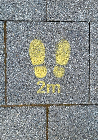 Weston-super-Mare, UK - April 9, 2021: A sign stencilled on a pavement warning those queueing to...