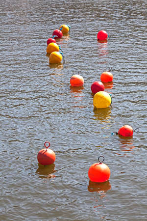 A series of small red, yellow, and orange buoys on the Floating Harbour in Bristol, UK