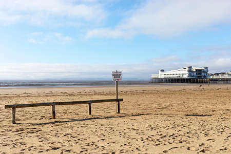Weston-super-Mare, UK - September 24, 2021: A sign advertising donkey rides on the beach with the Grand Pier in the backgroundのeditorial素材