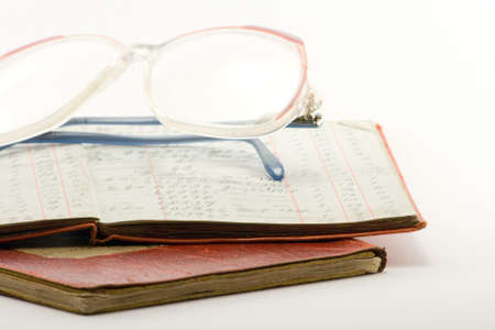 two financial ledgers and a pair of glasses on a white backgroundの写真素材