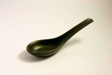 Black chinese china soup spoon on a white backgroundの写真素材