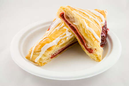Sliced cherry danish pastry on a plate with a white backgroundの写真素材