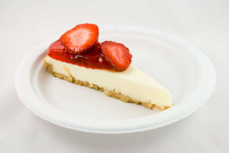 Slice of strawberry chessecake on a white plate with a white backgroundの写真素材