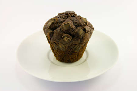 Single chocolate muffin on a white plate with a white backgroundの写真素材