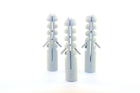 Three grey plastic wall plugs in a triangle on a white backgroundの写真素材