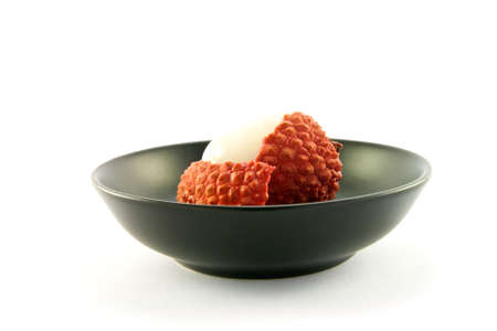 Single peeled lychee in a black dishの写真素材