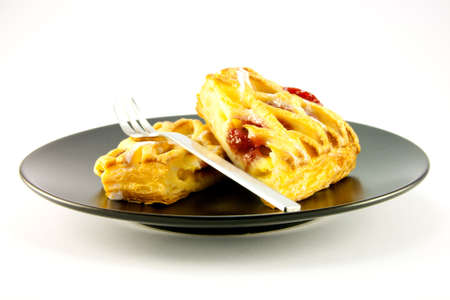 Raspberry and custard danish on a black plate with a fork on a white backgroundの写真素材