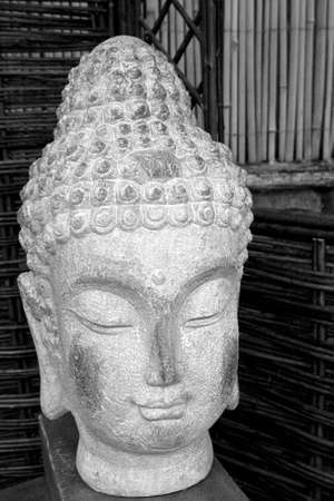 Black and white buda head statue made of stone situated in a gardenの写真素材