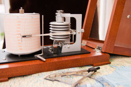 Barograph in a wooden box with the lid open standing on a mapの写真素材