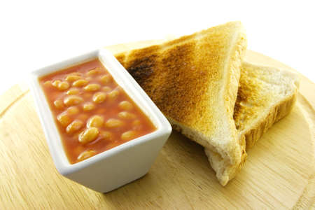 Delicious cooked breakfast items with toast and baked beans on a plate on a white background