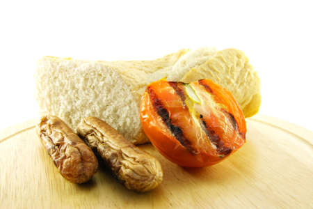 Delicious cooked breakfast items with baguette and char-grilled tomato on a plate on a white backgroundの写真素材