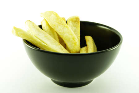 Golden cooked frys in a small black bowl on a white backgroundの写真素材