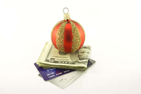 Single red and gold christmas bauble with folded dollar bills and two plastic credit cards on a white reflective backgroundの写真素材