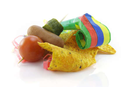 Baked spicy nachos with cocktail stick containing tomato, hot dog and gherkin with blower and party...