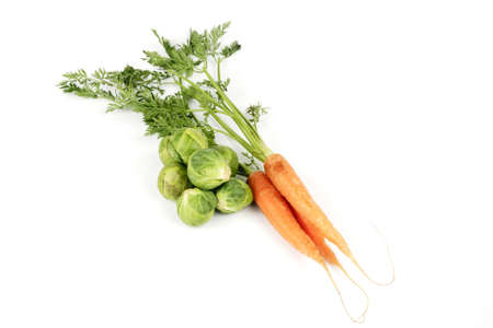 Bunch of ripe crunchy carrots and a pile of green sprouts on a reflective white backgroundの写真素材