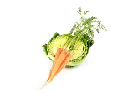 Half a raw green cabbage with a bunch of raw carrots on a reflective white backgroundの写真素材