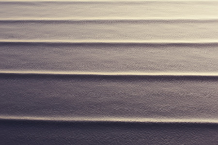 wave patterns created on a calm ocean with a backlit evening sun to highlight the movements