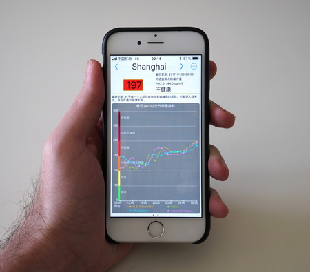 Wuhan China, 9 December 2017: Man holding smartphone with AQI air quality index apps showing red...