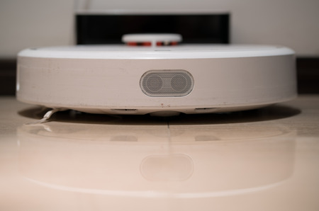Generic white robotic vacuum cleaner front view recharging on the baseの写真素材