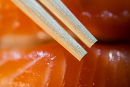 Disposable bamboo chopsticks and salmon sushi in background macro shotの写真素材
