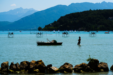 Silhouette of an unrecognizable beautiful woman walking in middle of Annecy lake toward her pedalo in Savoy Franceの写真素材
