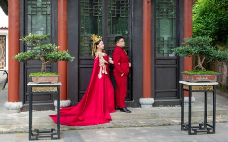 25 April 2018, Wuhan China : Chinese couple with traditional red costumes posing for wedding pictures at Qingchuan Pavilion in Wuhan Chinaのeditorial素材