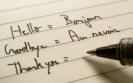 Beginner French language learner writing words in French for homework on a notebook close-up shot