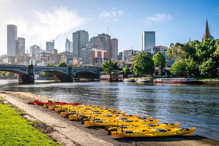 4 January 2019, Melbourne Vic Australia : Melbourne buildings skyline with Yarra river view and yellow kayak boats on the riverbank in Melbourne Victoria Australiaのeditorial素材