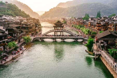 2 June 2019, Fenghuang China : Tuo Juang river scenery with antique bridge and dramatic light in Fenghuang phoenix town in Hunan Chinaのeditorial素材
