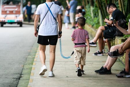 Chengdu China, 4 August 2019 : Mother and her kid tethered with a strap leash in Chinaのeditorial素材