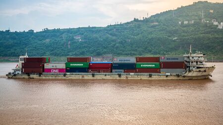 Chongqing China , 8 August 2019 : Container cargo ship side view on Yangtze river with Evergreen and Minsheng containers in Chinaのeditorial素材