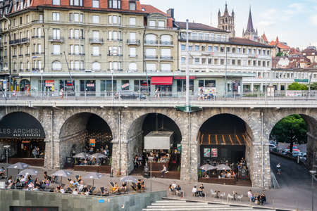 Lausanne Switzerland, 25 June 2020: Les arches a bar with a terrace full of people under Grand-Pont bridge arches and city view during 2020 covid crisis in Le Flon district Lausanne Switzerlandのeditorial素材